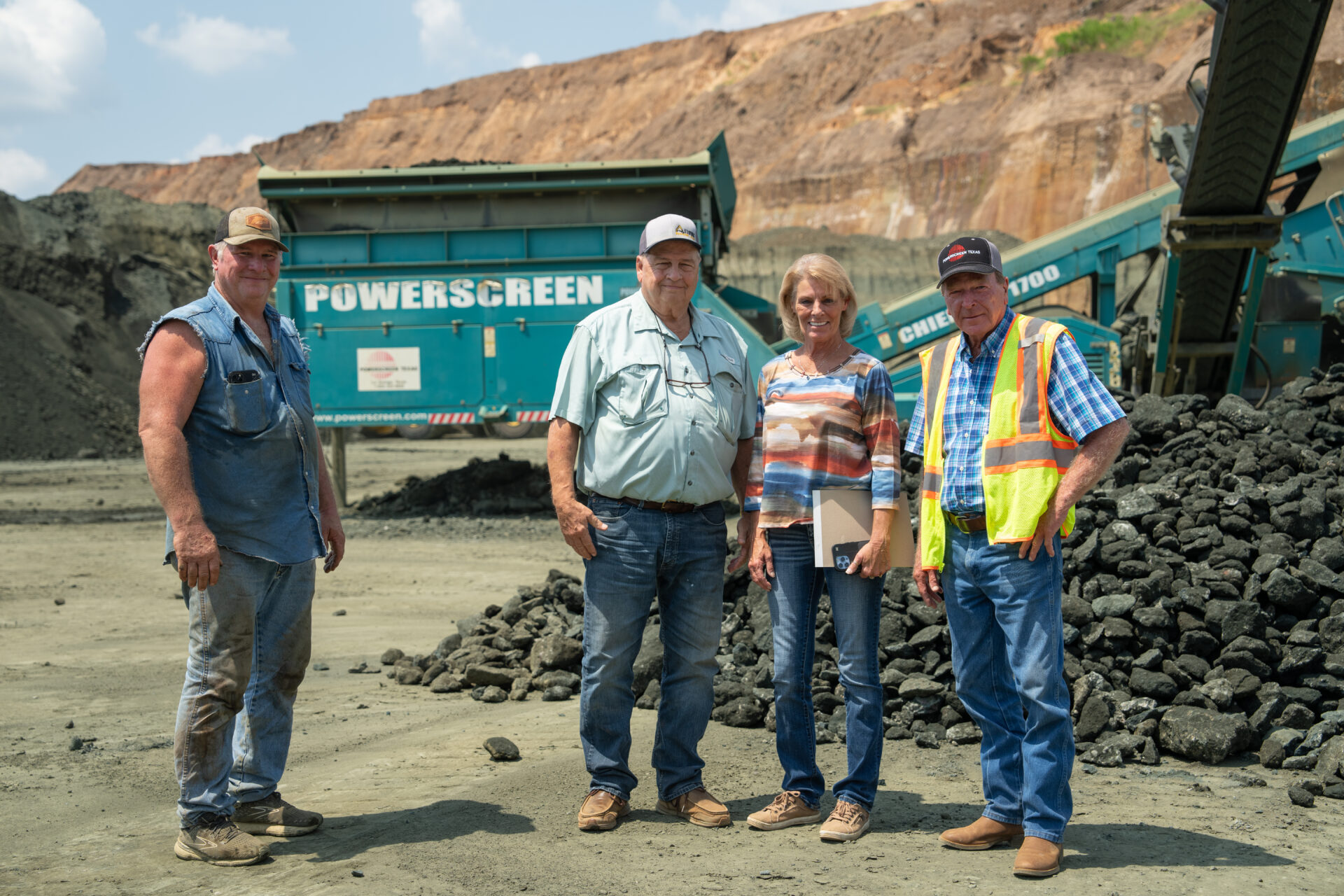 People standing in front of a green machine in a quarry