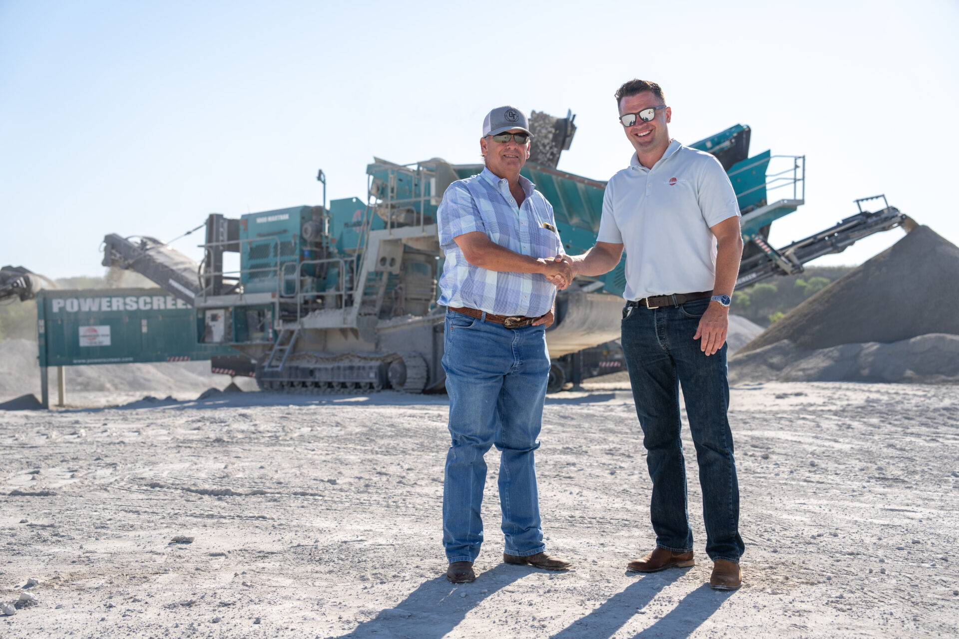 two men shaking hands in front of a set up of blue machines