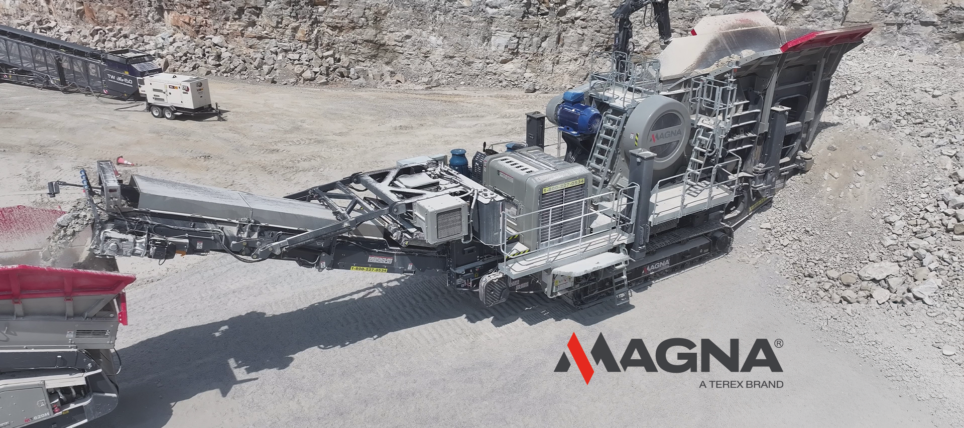 MAGNA tracked jaw crusher operating in a quarry, processing stone with conveyors moving crushed material, branded with the MAGNA Terex Brand logo.