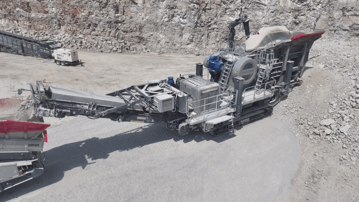 MAGNA tracked jaw crusher processing rock at a quarry face, with conveyors moving crushed material to downstream equipment.
