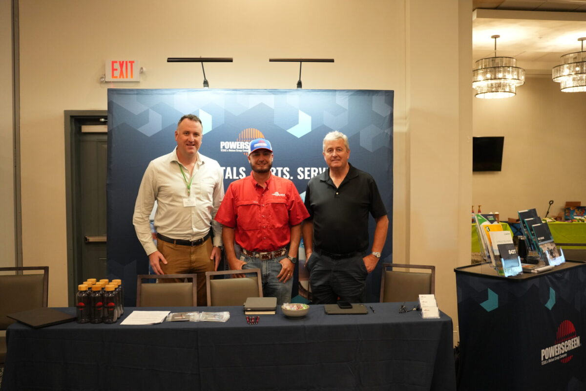 Three men standing in an exhibitor booth at a composting event